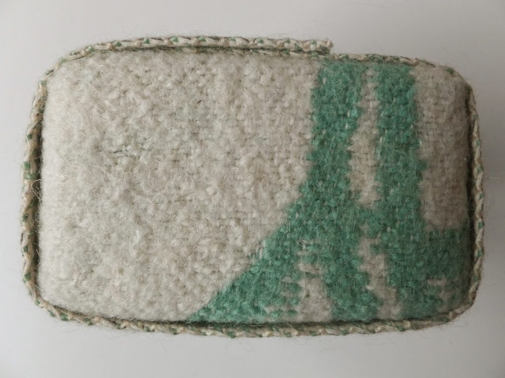  Karakter van wollen deken uit ‘Geborgen herinneringen’ van Jeanne de Bie met de kleuren groen en wit / beige met lichte achtergrond textielkunst. 
