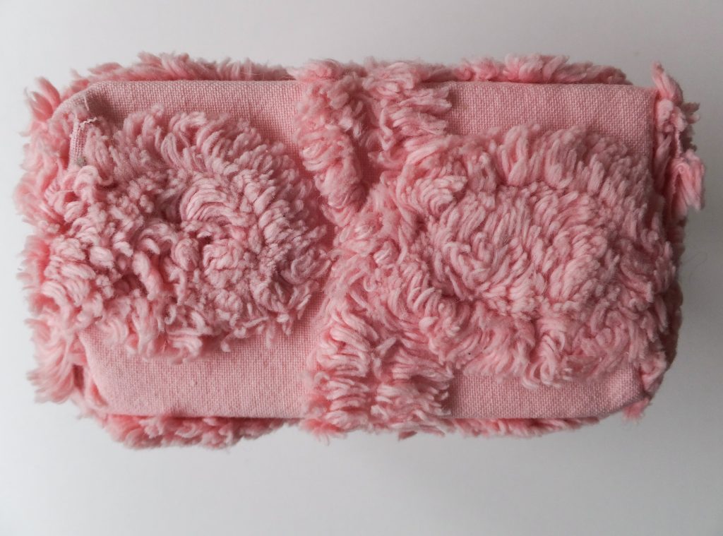  Roze karakter van wollen deken uit ‘Geborgen herinneringen’ (Salvaged memories) van Jeanne de Bie, zacht en fluffy, tegen lichte achtergrond. 