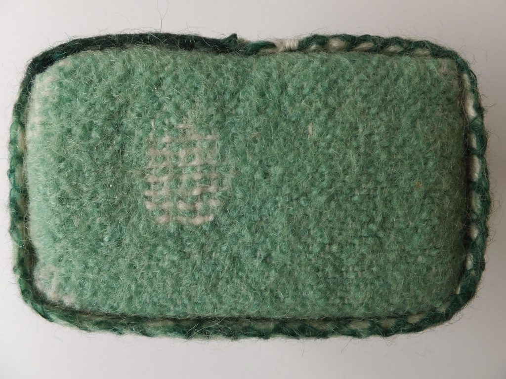 Groen met wit rechthoekig karakter van wollen deken uit ‘Geborgen herinneringen’ (Salvaged memories) van Jeanne de Bie textielkunst over verleden